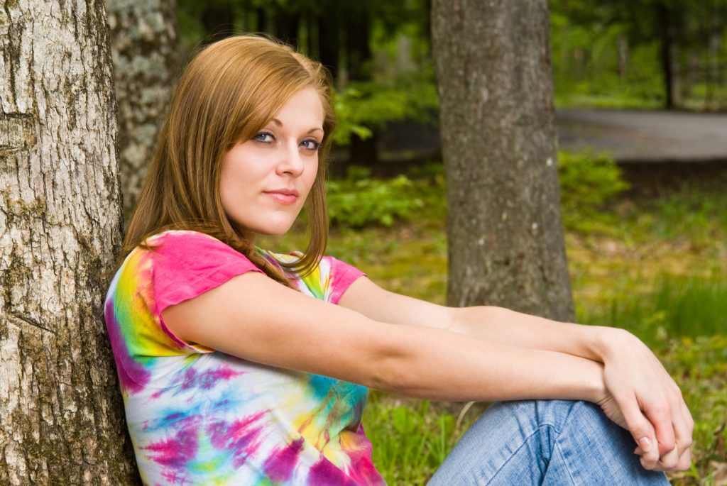 Woman Sitting Against a Tree in a Tie Dye shirt