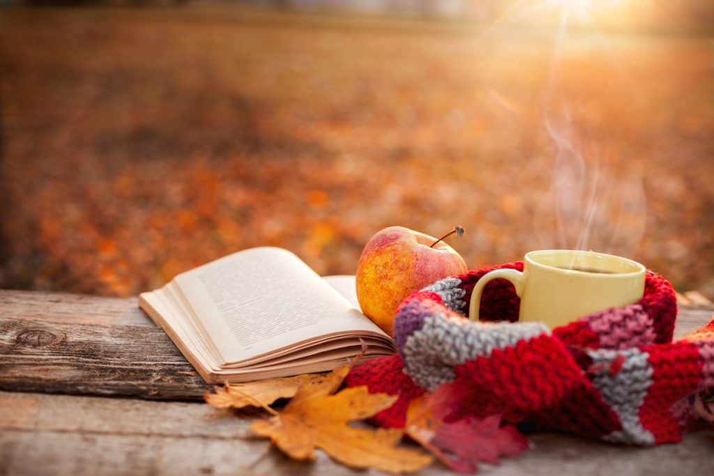 Tea mug with warm scarf open book and apple for fall festivities checklist